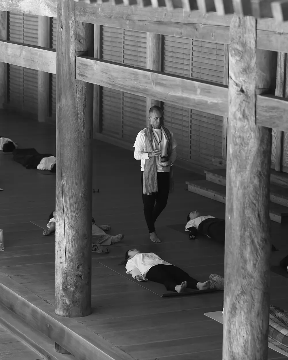 Andrei Ram, de pie con un cuenco en las manos, guía a un grupo acostado en el suelo de madera de un templo en Japón